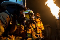 U.S. Air Force Chief Master Sgt. Jennifer Brembah, 52nd Mission Support Group chief enlisted manager, and Col. Steven Zubowicz, 52nd MSG commander, experience a controlled fire during a live fire exercise at Spangdahlem Air Base, Germany, March 23, 2017. The training provided Spangdahlem firefighters with experience in hose advancement and extinguishing various types of fires in a three-room trailer. (U.S. Air Force photo by Airman 1st Class Preston Cherry)