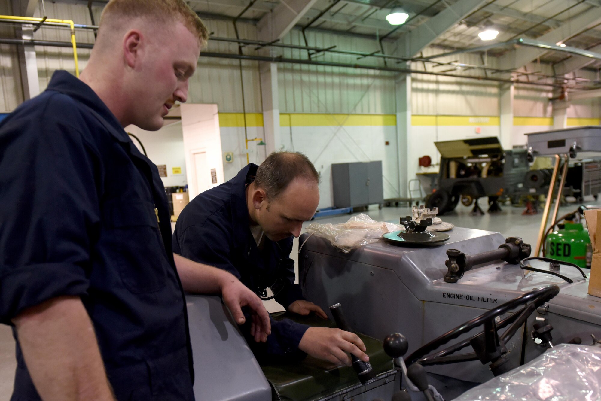 Senior Airman Nicholas Cerwonka (left), 4th Equipment Maintenance Squadron aerospace ground equipment technician, discusses repairs to a bomb lift with Staff Sgt. Patrick Sellers (right), 4th EMS AGE technician, March 15, 2017, at Seymour Johnson Air Force Base, North Carolina. AGE Airmen repair equipment used by aircraft maintainers on the flight line. (U.S. Air Force photo by Airman 1st Class Victoria Boyton) 