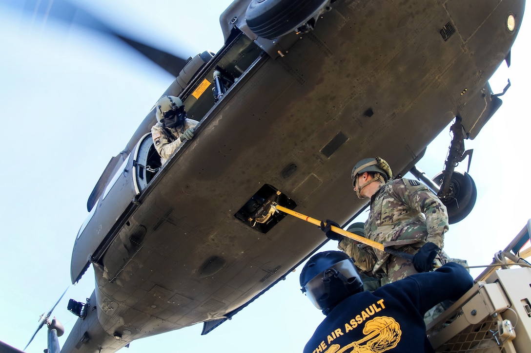A soldier holds a static discharge wand against the cargo hook on a UH-60 Black Hawk helicopter at Fort Bragg, N.C., March 23, 2017. Army photo by Capt. Adan Cazarez