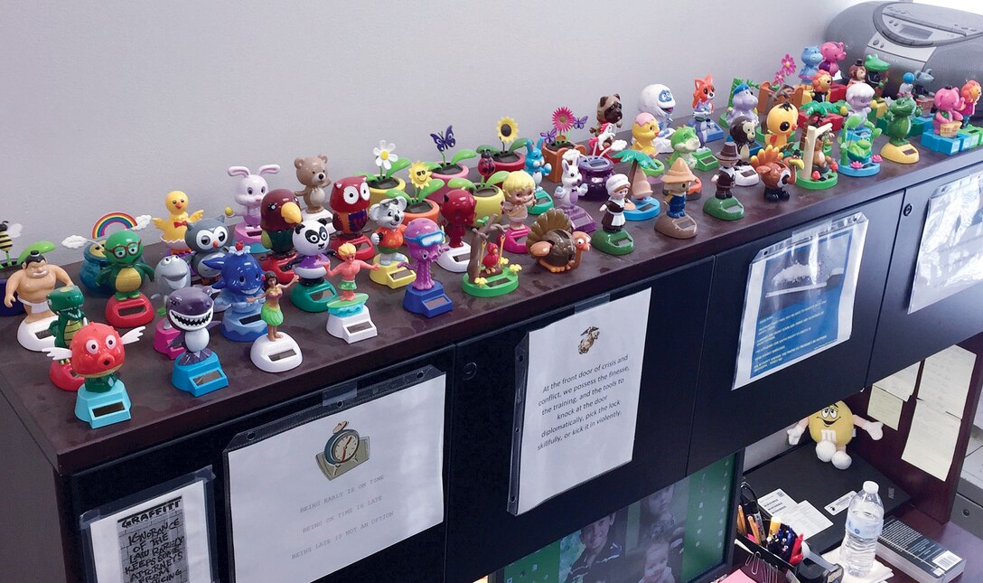 One hundred twenty-five solar panel bobble head toys line the desk and bookshelf of Barbara Flores, legal administrative assistant with Quantico's staff judge advocate office.