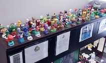 One hundred twenty-five solar panel bobble head toys line the desk and bookshelf of Barbara Flores, legal administrative assistant with Quantico's staff judge advocate office.