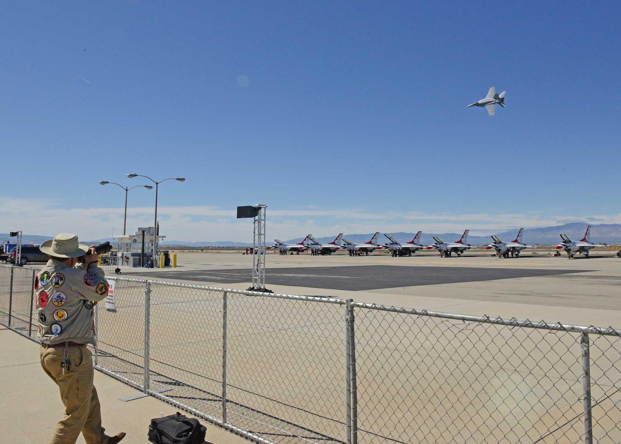 A U.S. Navy F/A-18C Hornet flies over F-16 Fighting Falcons belonging to the U.S. Air Force Thunderbirds Demonstration Team March 24 at General William J. Fox Airfield in Lancaster, California. The Hornet is from the U.S. Navy’s Tac Demo Team, which highlighted the mobility, versatility and power of the F/A-18 during the 2017 L.A. County Air Show March 25-26. (U.S. Air Force photo by Kenji Thuloweit)