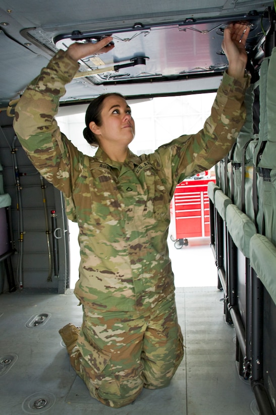 Army Pfc. Meghan Aube checks an emergency hatch on an UH-60 Blackhawk helicopter at the Army Aviation Support Facility in Frankfort, Ky., March 16, 2017. Kentucky Army National Guard photo by Staff Sgt. Scott Raymond