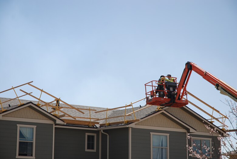 Workers use a lift to make repairs on the roof of a housing unit on Peterson Air Force Base, Colo., March 23, 2017. Thousands of windows on hundreds of housing units, along with roofing and solar panels, were damaged during the July 28, 2016, hail storm that hit the Pikes Peak Region. Crews are working extended hours to repair the damage. 