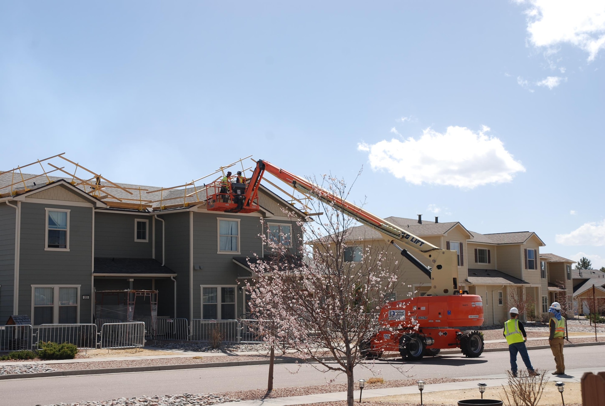 Workers use a lift to make repairs on the roof of a housing unit on Peterson Air Force Base, Colo., March 23, 2017. Thousands of windows on hundreds of housing units, along with roofing and solar panels, were damaged during the July 28, 2016, hail storm that hit the Pikes Peak Region. Crews are working extended hours to repair the damage. 