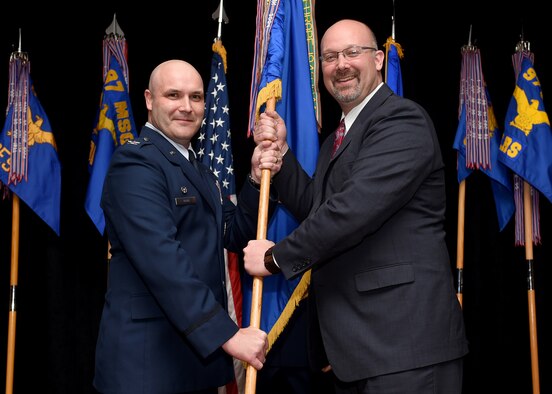 U.S. Air Force Col. Todd Hohn, 97th Air Mobility Wing commander, and Brian Bush, 97th Air Mobility Wing honorary commander and president of the Altus Chamber of Commerce, present the wing guidon during the Honorary Commander Induction Ceremony March 24, 2017, Altus Air Force Base, Oklahoma. Twenty-seven community members were inducted into the two-year program. (U.S. Air Force photo by Senior Airman Franklin R. Ramos/Released)