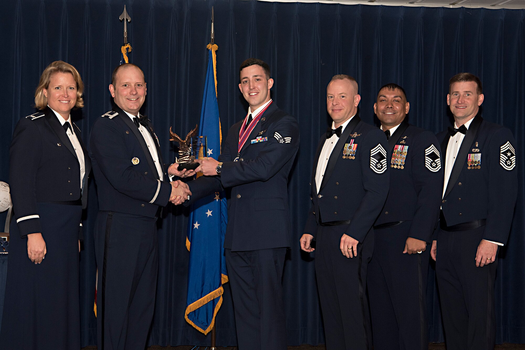 Col. Doug Schiess, 21st Space Wing commander presents the John L. Levitow award to Senior Airman Justin Cole, 50th Operational Support Squadron GPS qualification training course manager during an Airmen Leadership School graduation at Peterson Air Force Base, Colo., March 21, 2017. The John L. Levitow award is awarded to the distinguished graduate from each class of the ALS and is named in honor of John L. Levitow, the lowest ranking Airmen to ever receive the Medal of Honor. 