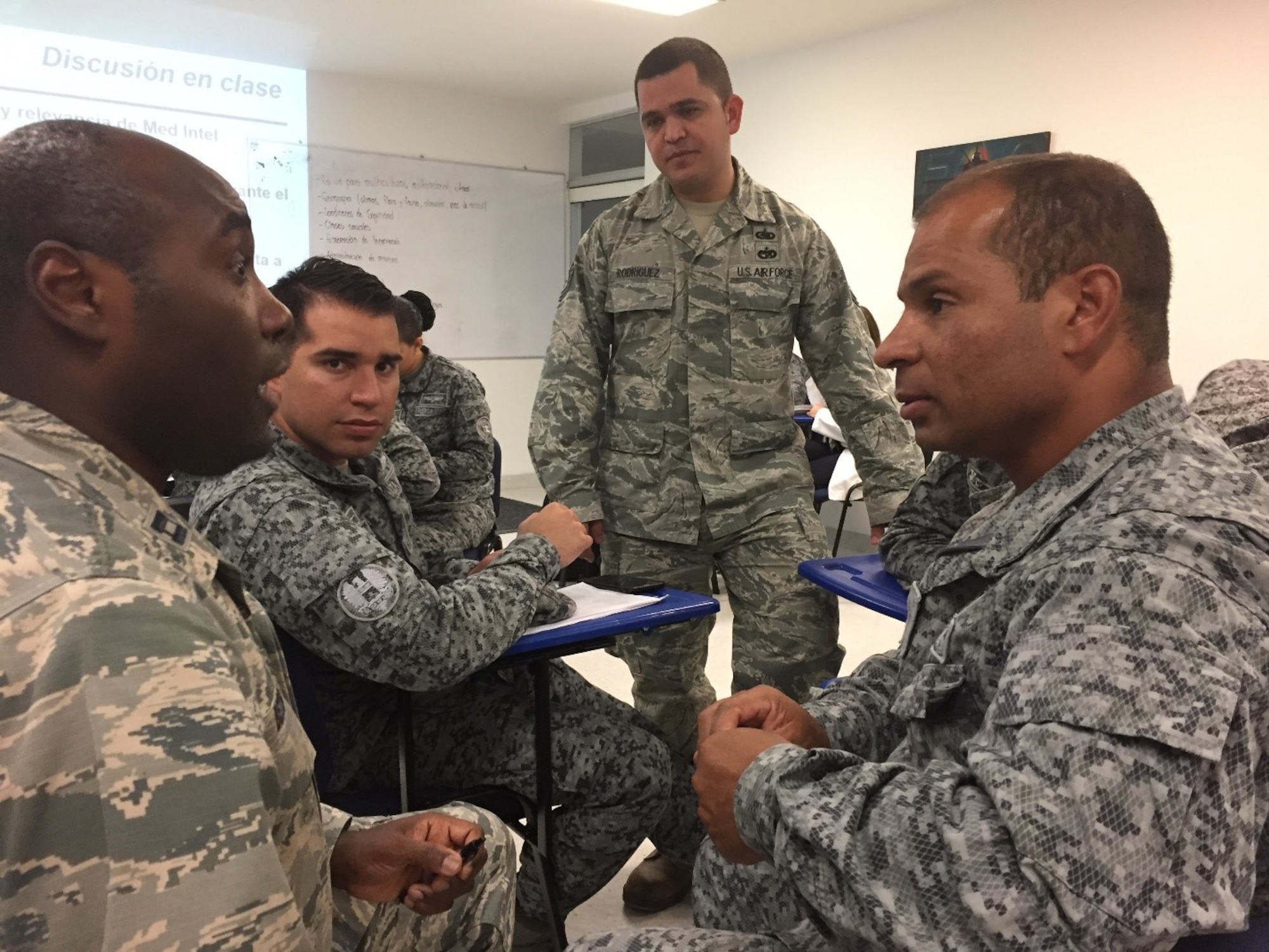 Tech. Sgt. Filberto Rodriguez, center, 571st Mobility Support Advisory Squadron Air Advisor, prepares to translate for an augmentee providing medical intelligence training to members of the Colombian Air Force in Bogota, Colombia. The 571st MSAS alongside Airmen from five other squadrons spent three weeks training the Colombian forces in air operations, aeromedical evacuation, propeller balance, zodiac rigging and medical intelligence courses. (Courtesy Photo)  