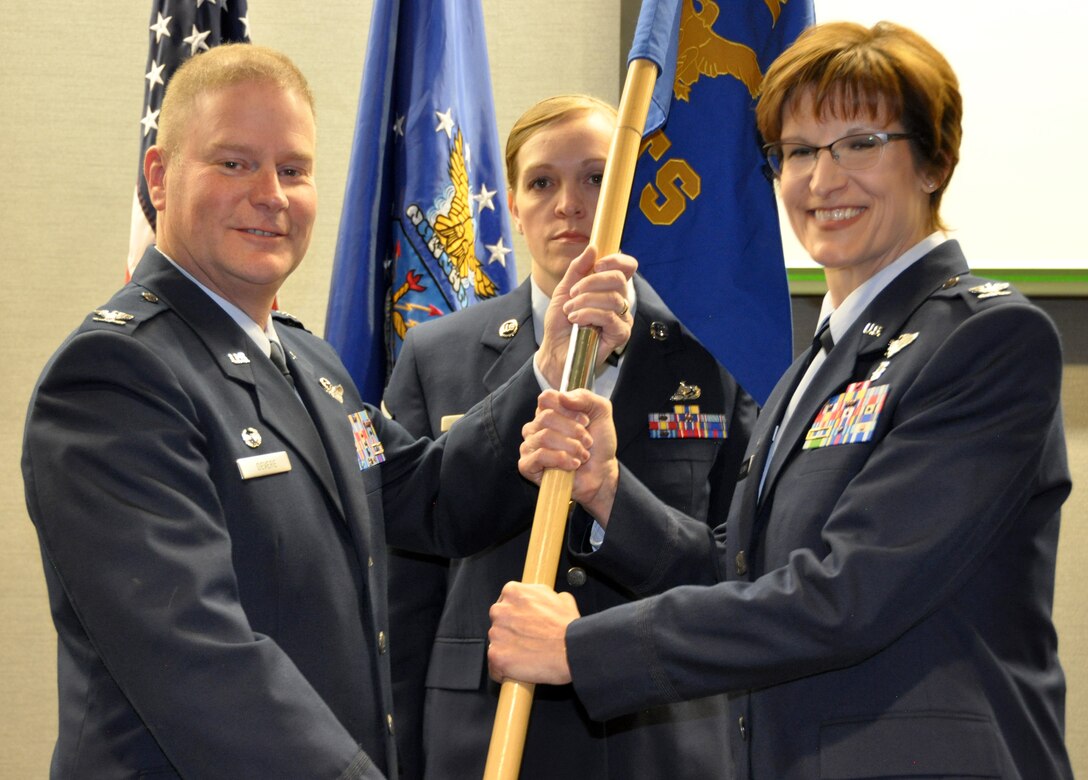 During an assumption-of-command ceremony, Col. Karen Steiner (right) accepts the 302nd Aeromedical Staging Squadron guidon from Col. James DeVere, the 302nd Airlift Wing commander,    while the squadron’s first sergeant, Master Sgt. Cortney Shank, looks on at Peterson Air Force Base, Colorado, March 5, 2017.,. (U.S. Air Force photo/1st Lt. Stephen J. Collier)