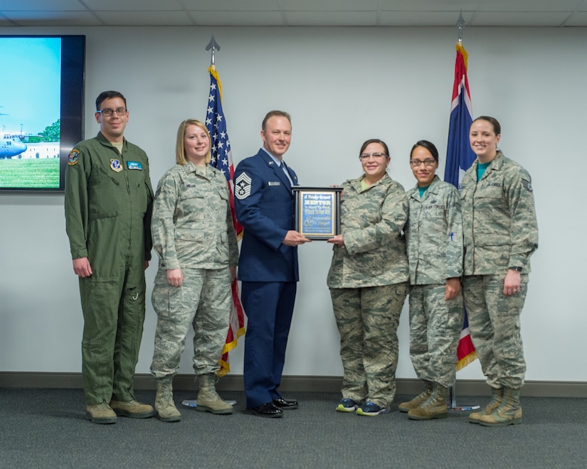 U.S. Air Force Staff Sgt. Rebekah Miller (second from the left) stands with other members of the Rising 6 Council as they make a presentation to retiring Chief Master Sgt. Michael Abbott, Mar. 10, 2017 in Cheyenne, Wyoming. Miller has been with the Wyoming Air National Guard for six years and is serving as a command post specialist. She has also been an officer with the Torrington police department for two years. (U.S. Air National Guard photo by Senior Master Sgt. Charles Delano/released)