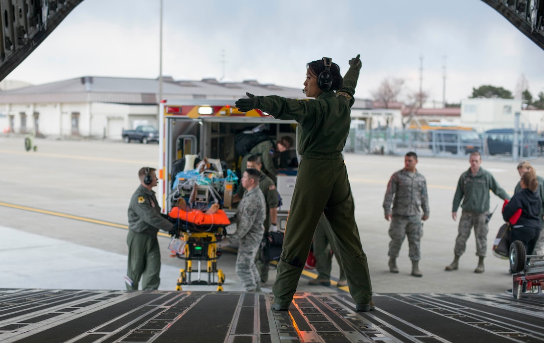 U.S. Air Force Capt. Lynn Nguyen, an 18th Aeromedical Evacuation Squadron flight nurse, guides medical personnel onto a C-17 Globemaster III during an aeromedical evacuation at Misawa Air Base, Japan, March 22, 2017. (U.S. Air Force photo by Senior Airman Brittany A. Chase)
