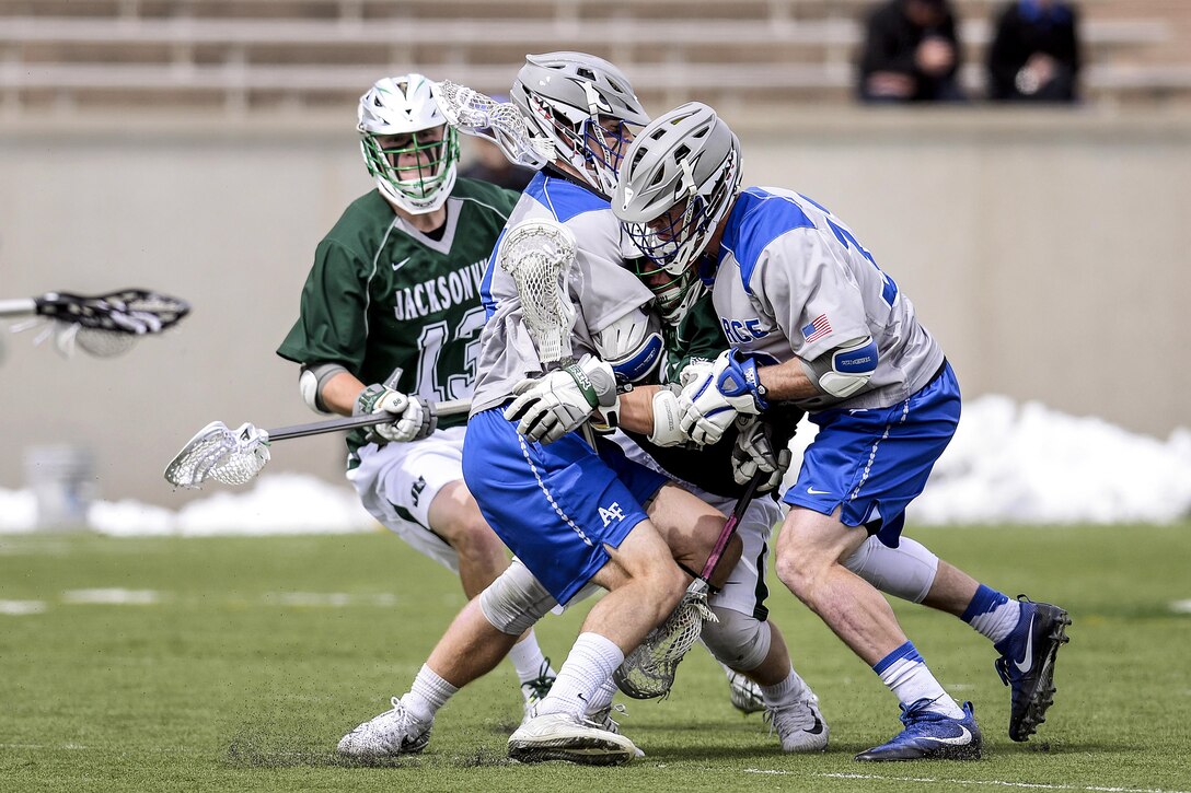 Nick Hruby, a junior, and Trent Harper, a sophomore, crush Jacksonville's Hunter Forbes as they fight for the ball as the U.S. Air Force Academy Falcons met the Jacksonville University Dolphins in Falcon Stadium in Colorado Springs, Colo., March 25, 2017.  An overtime goal lifted the Falcons to a 10-9 win, as they improve to 6-3 overall with a 2-0 record in Southern Conference play. Air Force photo by Mike Kaplan