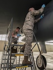 (From left) Airman 1st Class Zachary Campfield and A1C Carlos Ramirez, 5th Maintenance Squadron crew chiefs, peel tape from a B-52H Stratofortress at Minot Air Force Base, N.D., March 20, 2017. These crew chiefs perform daily aircraft maintenance, to include diagnosing malfunctions and replacing damaged components. (U.S. Air Force photo/Airman 1st Class Jonathan McElderry)