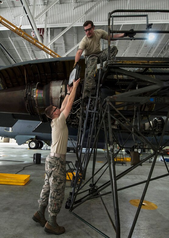 (From left) Airman 1st Class Zachary Campfield, 5th Maintenance Squadron crew chief, hands a laptop to Staff Sgt. Alex Yount, 5th MXS crew chief, at Minot Air Force Base, N.D., March 20, 2017. The 5th MXS crew chiefs follow step-by-step instructions on the laptops when performing aircraft maintenance. (U.S. Air Force photo/Airman 1st Class Jonathan McElderry)