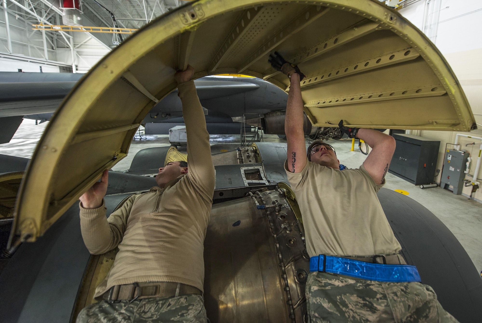 (From left) Senior Airman Allan Jungst and Staff Sgt. Alex Yount, 5th Maintenance Squadron crew chiefs, rotate an upper wrap cowling at Minot Air Force Base, N.D., March 20, 2017. During a phase inspection for 18 consecutive days, these maintainers wash, lubricate, inspect and fix all identified discrepancies on the B-52H Stratofortress. (U.S. Air Force photo/Airman 1st Class Jonathan McElderry)