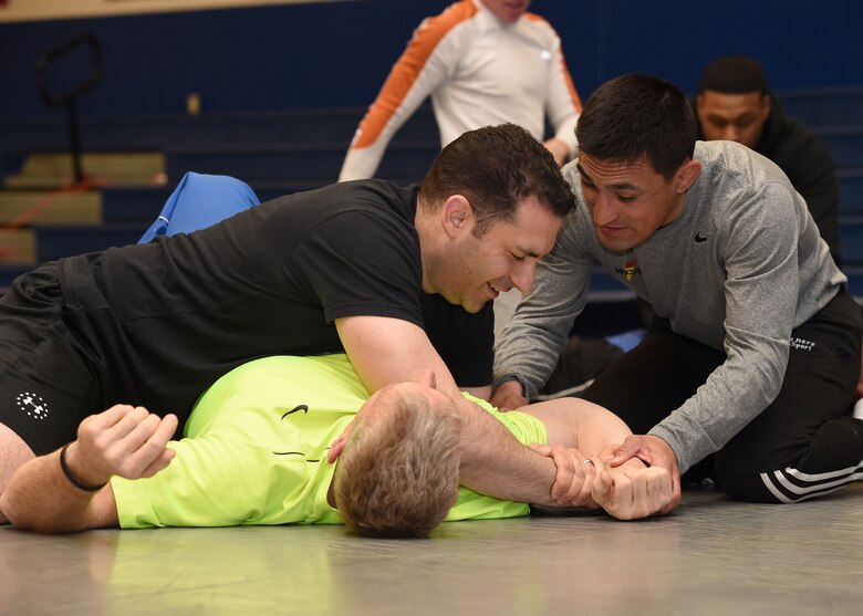 SCHRIEVER AIR FORCE BASE, Colo.— Marco Lara, lead combative class instructor provides instruction to Jason Janaros, as he grapples with Adam Edwards, during a combative class at Schriever Air Force Base, Colorado, Wednesday, March 29, 2017. The hourlong class covered basic mount and guard positioning, arm bar, bent arm bar and rear naked chokes submissions. (U.S. Air Force photo/Staff Sgt. Matthew Coleman-Foster)