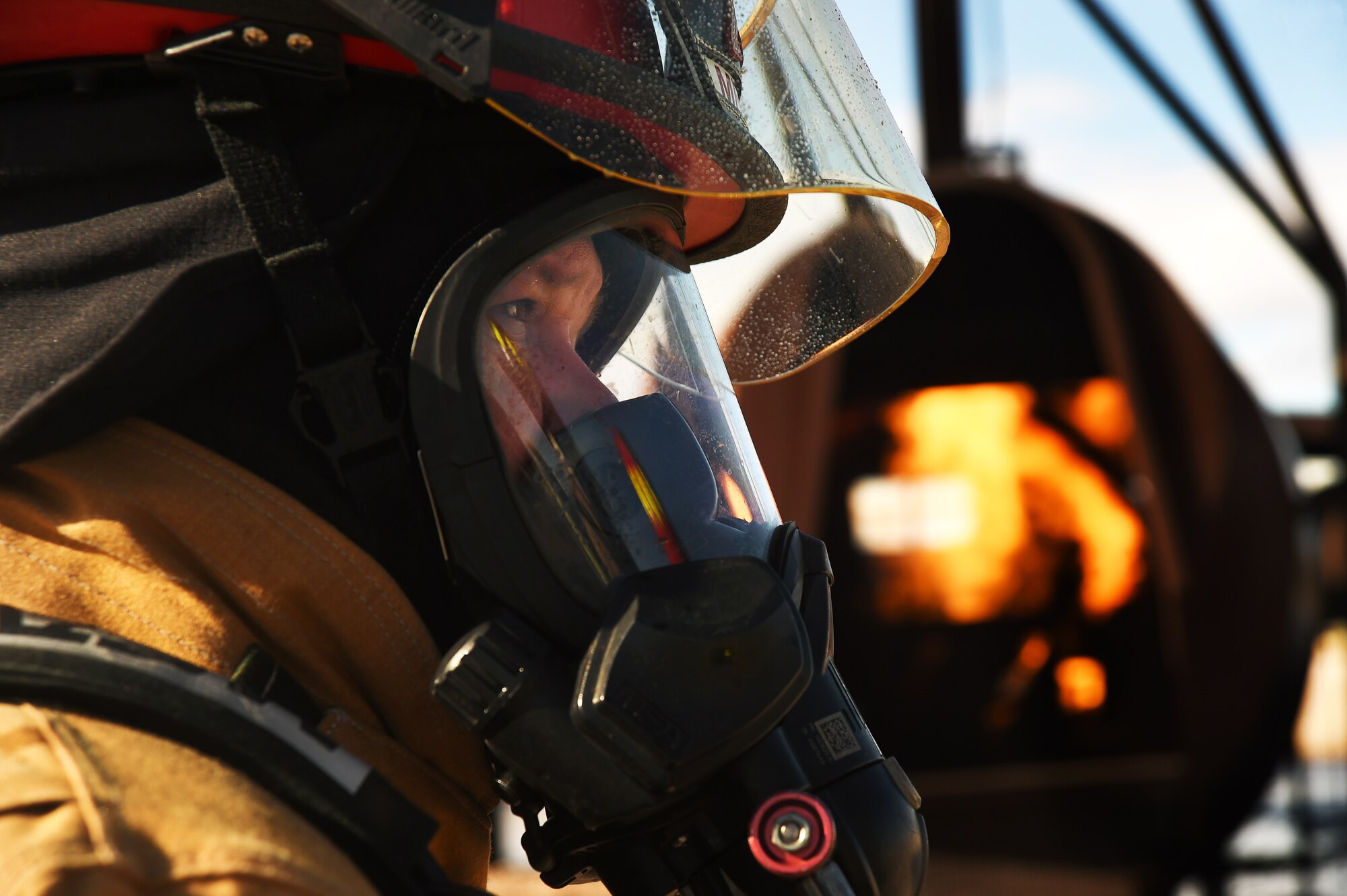 An Airman assigned to the 99th Civil Engineer Squadron Fire Protection Flight peers at the training instructor before beginning an aircraft live fire training exercise March 23, 2017, at Nellis Air Force Base, Nev. Firefighters are required to complete the exercise semi-annually in order to stay current with training requirements. (U.S. Air Force photo/Airman 1st Class James Thompson) 