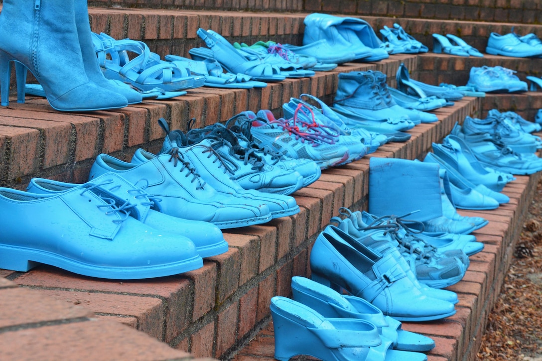 Military members and sexual assault response coordinators display shoes painted in blue.