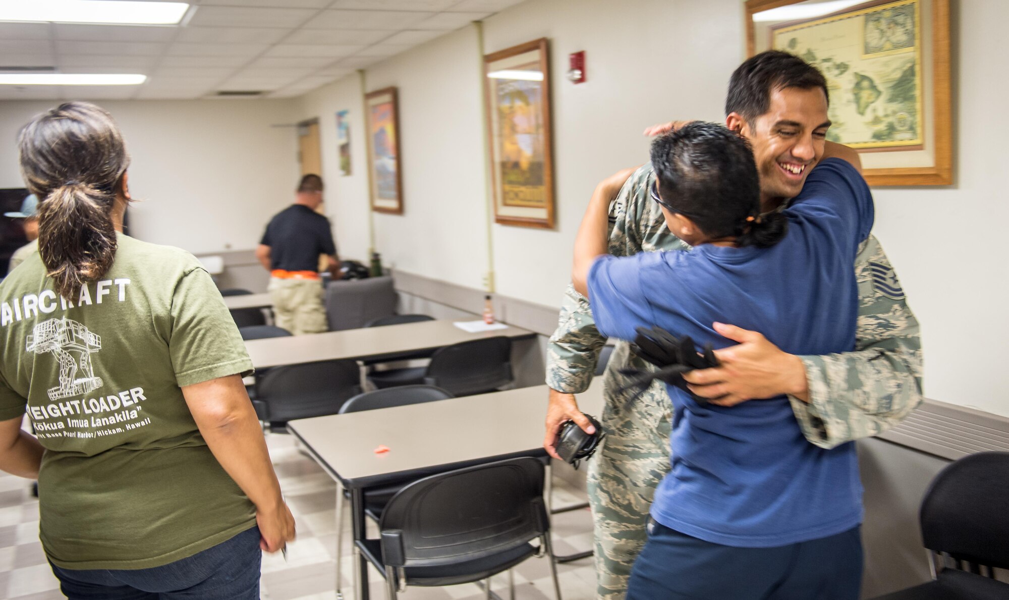 Then Tech. Sgt. Alfred Van Gieson, now Master Sgt., is hugged by co-worker Kalei Agapay, a special handler, and Ululant Luis, left, a load planner in break room of the 48th Aerial Port Squadron, 624th Regional Support Group, Joint Base Pearl Harbor-Hickam, Oahu, Hawaii, Aug 13, 2016. Van Gieson, an Air Force reservist, is a veteran of Operation Iraqi Freedom, a world champion outrigger, or Va'a, paddler was trained in aircraft loading byLuis when the two worked for Aloha Airlines. (U.S. Air Force photo by J.M. Eddins Jr.)
