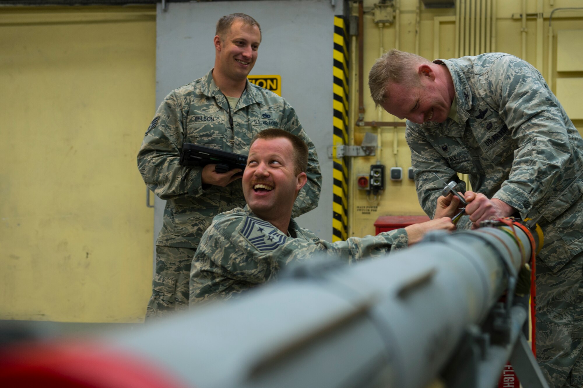U.S. Air Force Chief Master Sgt. Edwin Ludwigsen 52nd Fighter Wing command chief and Col. Joseph McFall, 52nd FW commander, secure attachments to an Air Intercept Missile 9 at Spangdahlem Air Base, Germany, March 27, 2017. Airmen from the 52nd Maintenance Squadron munitions section work around the clock to support day-to-day flying.(U.S. Air Force photo by Senior Airman Dawn M. Weber)
