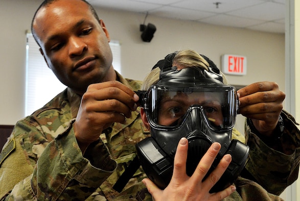 Capt. Matthew Thomas, Air Force Joint Test Program Office lead operation research systems analyst from Nellis Air Force Base, Nev., adjusts the gas mask of Master Sgt. Amanda Simonsen, 627th Civil Engineer Squadron commanders support staff section chief from Joint Base Lewis-McChord, Wash., during a chemical warfare class at Shaw AFB, S.C., Feb. 21, 2017. As part of their third week of training, the Rear Mission Support Element course students complete individual readiness tasks including chemical warfare and small arms qualification. (U.S. Air Force photo by Senior Airman Diana M. Cossaboom)
