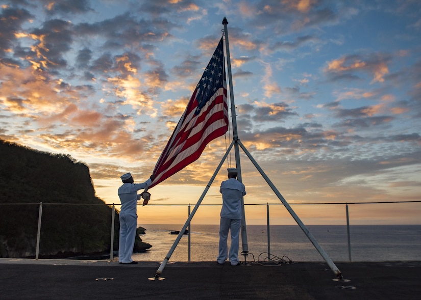 Navy Seaman Stephen Mugo and Petty Officer 3rd Class Jeremy Boling lower the U.S. flag at sunset during evening colors duty aboard the aircraft carrier USS Carl Vinson in Guam, Feb. 11, 2017. In April, the Navy will be the first service with access to the new online Servicemembers Group Life Insurance enrollment system. The new system will be available to the rest of the uniformed services later this year. Navy photo by Petty Officer 2nd Class Sean M. Castellano