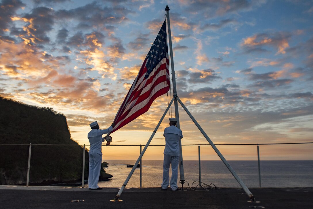 Navy Seaman Stephen Mugo and Petty Officer 3rd Class Jeremy Boling lower the U.S. flag at sunset during evening colors duty aboard the aircraft carrier USS Carl Vinson in Guam, Feb. 11, 2017. In April, the Navy will be the first service with access to the new online Servicemembers Group Life Insurance enrollment system. The new system will be available to the rest of the uniformed services later this year. Navy photo by Petty Officer 2nd Class Sean M. Castellano