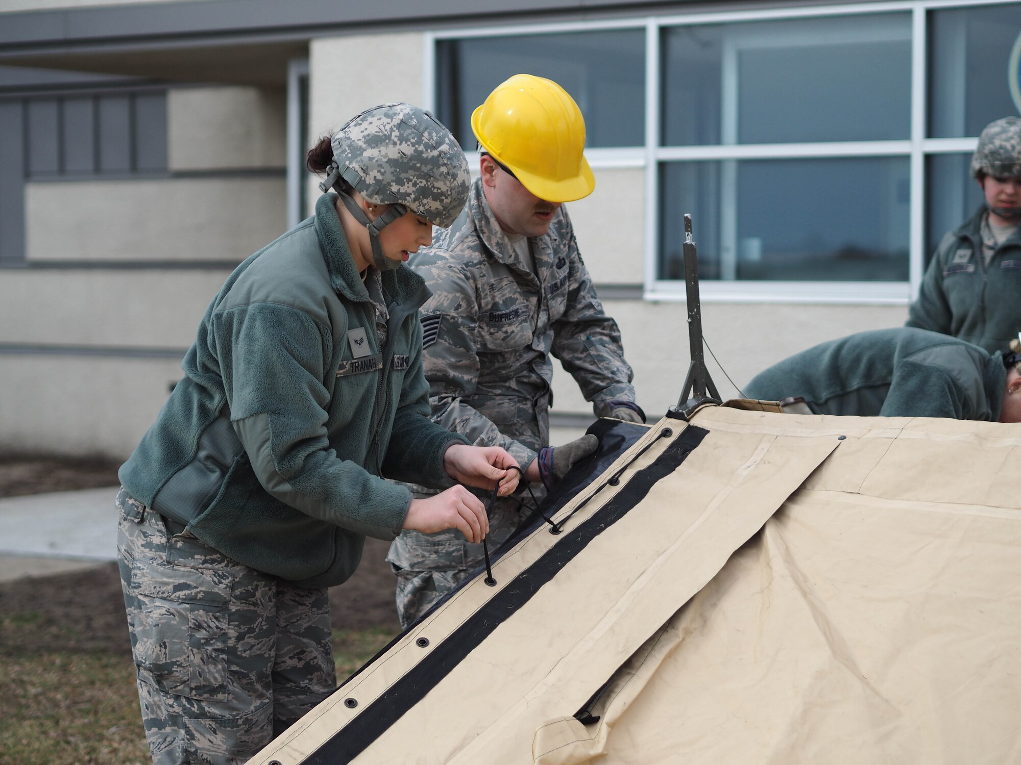 Senior Airman Paige Tranah (left) and Tech. Sgt. John Dufresne, 934th Force Support Squadron, attach the SPEK kitchen tent to the frame.