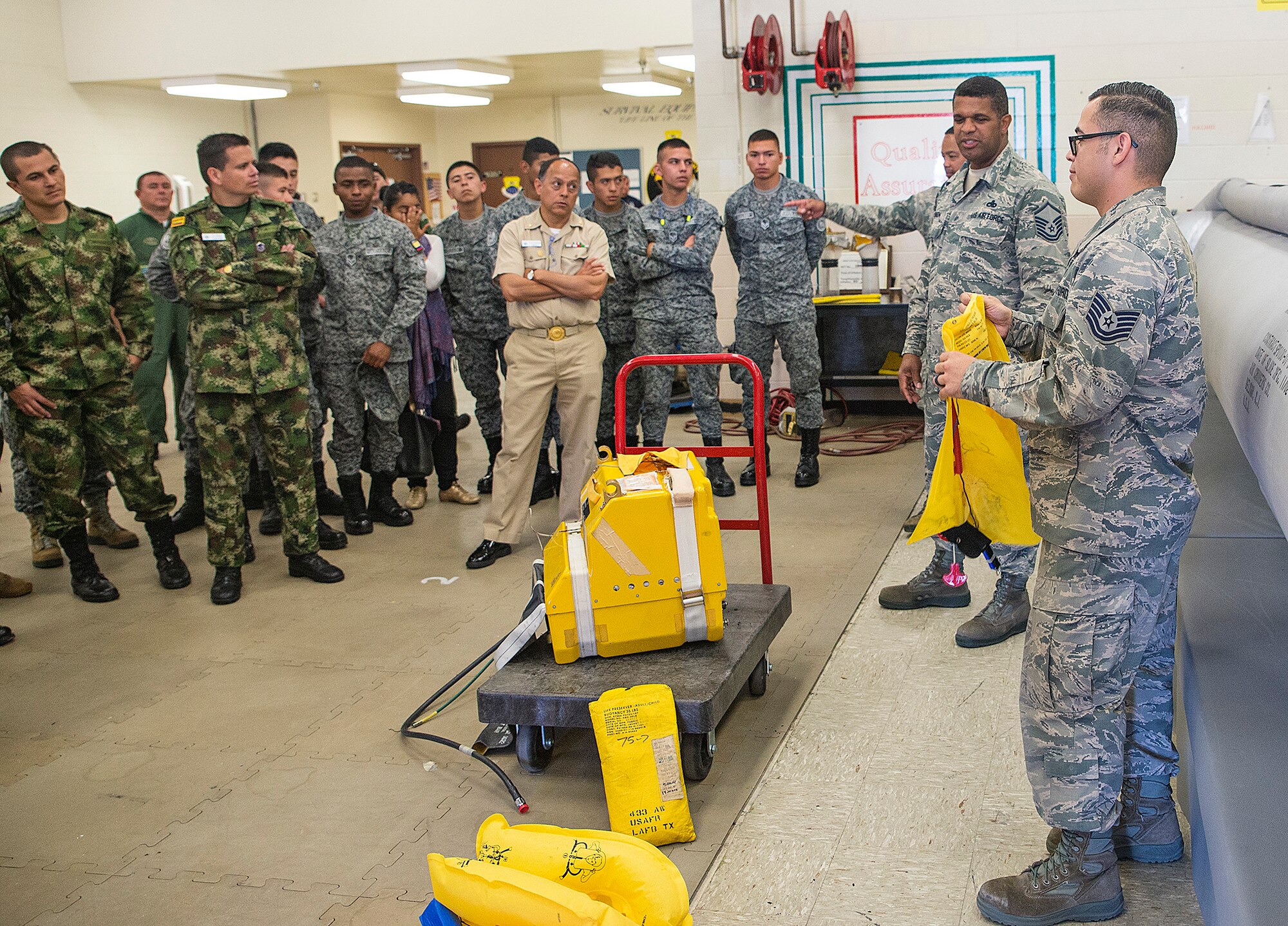 Tech. Sgt. Martin Alvarez, 433rd Operations Support Squadron aircrew flight equipment, shows students from the  Inter-American Air Forces Academy how to properly inflate a life preserver in the event of an emergency water egress March 29, 2017 at Joint Base San Antonio-Lackland, Texas. As part of their tour the students toured a C-5M Super Galaxy aircraft and visited structural, metals, and survival shops.  (U.S. Air Force photo by Benjamin Faske)