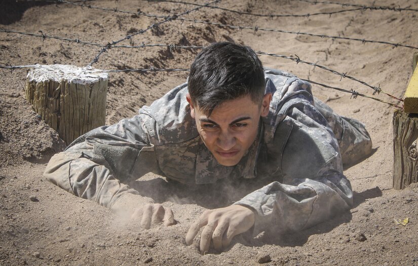 Army Reserve Spc. Julian Ditona (center), a multi-channel transmission systems operator/maintainer, assigned to the 98th Expeditionary Signal Battalion, 335th Signal Command (Theater), crawls under a barbwire obstacle at the obstacle course challenge at Fort Huachuca, Arizona March 28. Ditona and seven other Soldiers are competing in the command’s 2017 Best Warrior Competition, in hopes of representing their unit at the U.S. Army Reserve Commands 2017 Best Warrior Competition later this year. (Official U.S. Army Reserve photo by Sgt. 1st Class Brent C. Powell)
