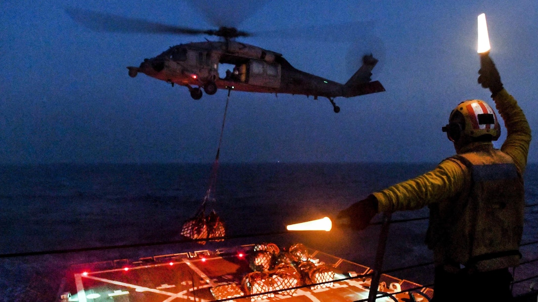 Navy Petty Officer 3rd Class Ronaldjay Juego signals to an MH-60S Seahawk helicopter as it brings cargo from the dry cargo ship USNS Charles Drew during a vertical replenishment aboard the guided-missile destroyer USS Wayne E. Meyer in the Pacific Ocean, March 27, 2017. Juego is a boatswain’s mate. Navy photo by Petty Officer 3rd Class Kelsey L. Adams