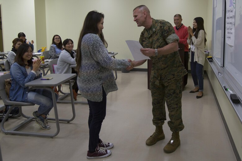 Col. Kevin A. Norton, right, awards Michelle Camina with a letter of appreciation during a ceremony March 29 aboard Camp Schwab, Okinawa, Japan. Camina is a volunteer teacher in the weekly adult English program. She was awarded for sacrificing her time to teach English to Okinawa residents. Norton is the Camp Schwab Camp Commander. 