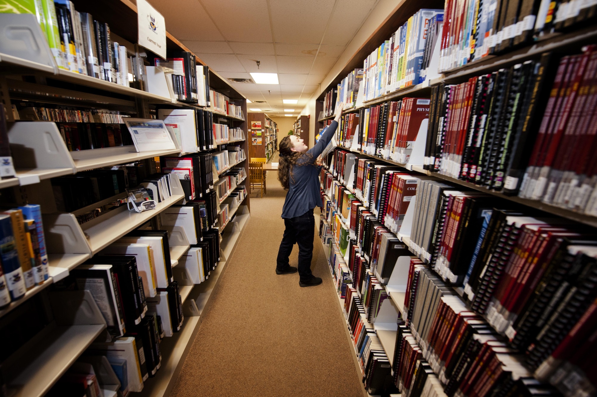 Marsha Adkins, 5th Forces Support Squadron library aide, shelves college level examination program books at Minot Air Force Base, N.D., March 21, 2017. The library was Air Force Global Strike Command’s 2016 Library of the Year, and has logged more reading time in the Summer Reading Program than any other AF base. (U.S. Air Force photo/Senior Airman J.T. Armstrong)