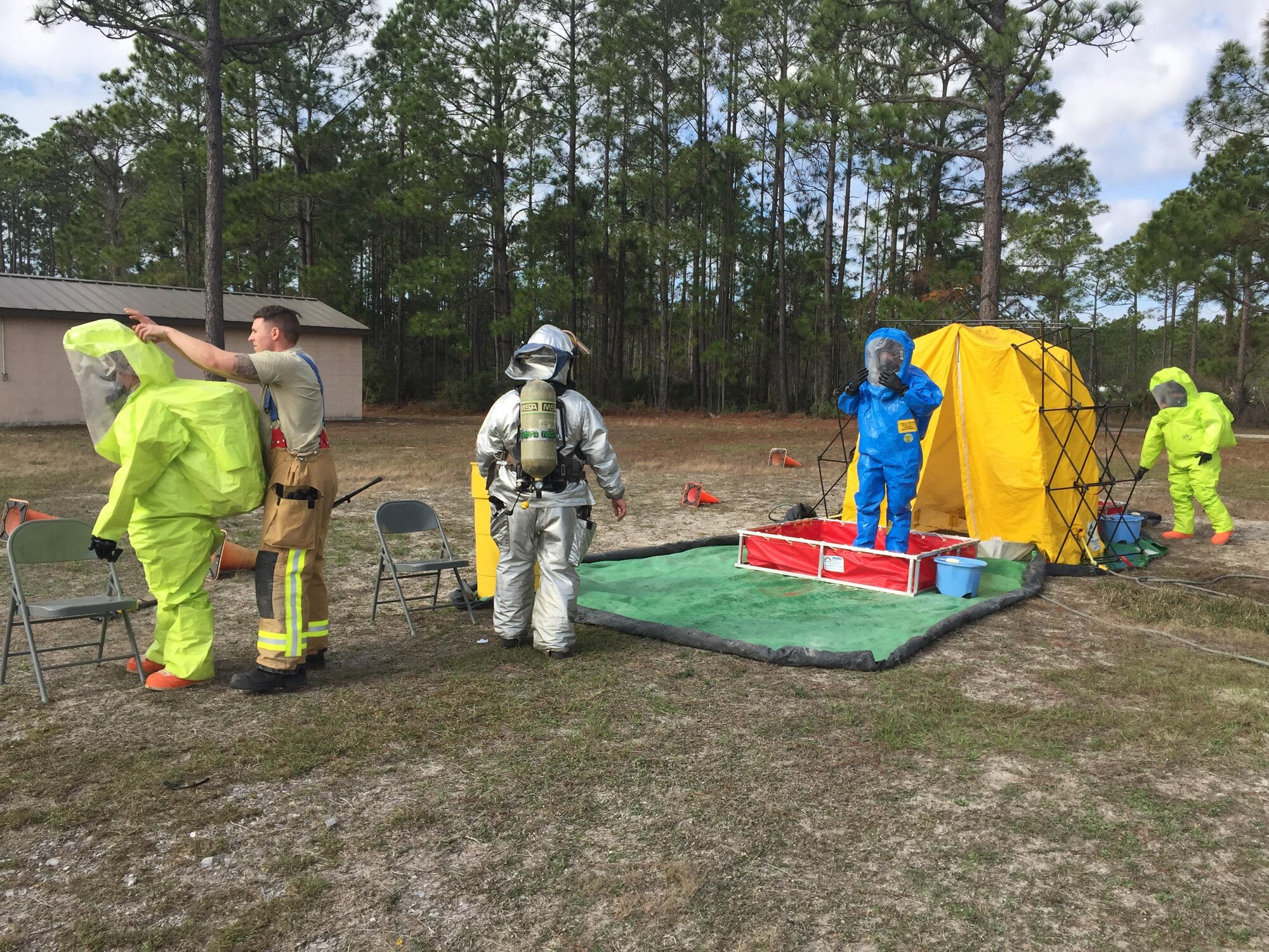 Emergency Management personnel in hazardous material suits process through a decontamination line during an exercise at Tyndall Air Force Base, Florida, January 25, 2017. The decontamination line was run by the fire department after an initial site survey during the exercise, which tested the EM personnel’s ability to properly react to finding a suspicious substance. (U.S. Air Force courtesy photo)