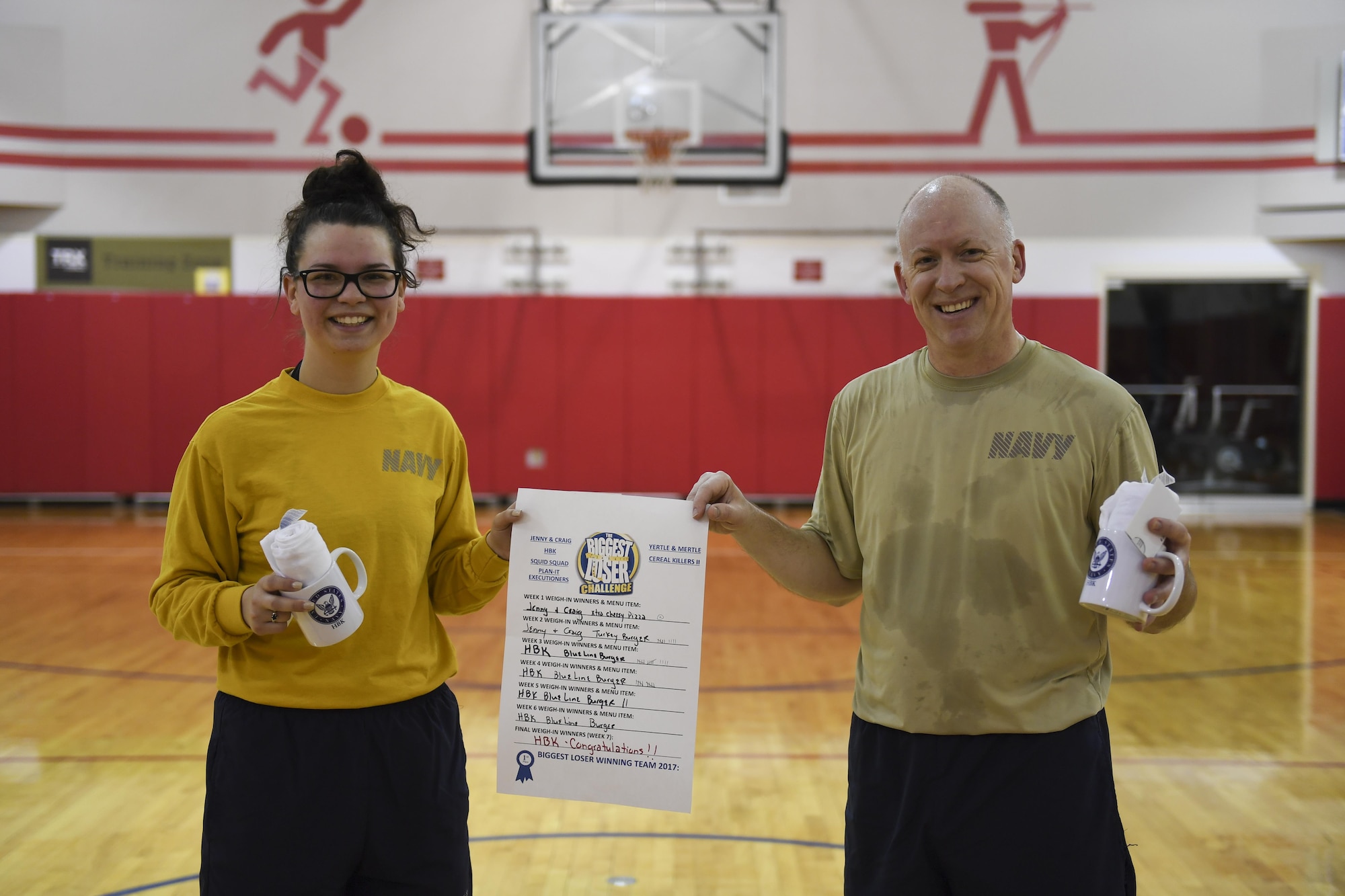 Cmdr. Don Haley, commander of the Navy Operational Support Center Pittsburgh, and Petty Officer 2nd Class Samantha Hamilton, funeral honors director with NOSC Pittsburgh hold a Biggest Loser challenge menu board at the Pittsburgh International Airport Air Reserve Station, March 30, 2017. At each weigh-in during the weight lost competition, the team with the most overall weight loss was given the opportunity to choose a menu item at Perksburgh, the local base café. (U.S. Air Force photo by Senior Airman Beth Kobily) 