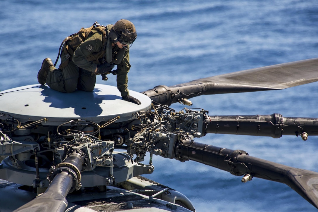 A Marine climbs to the top of a CH-53E Super Stallion to conduct maintenance during flight operations on the USS America in the Pacific Ocean, March 29, 2017. The America is underway with more than 1,000 sailors and 1,600 embarked Marines conducting Integration operations to prepare for the ship’s maiden deployment later this year. The Marine is assigned to Marine Medium Tiltrotor Squadron 161. Navy photo taken by Seaman Apprentice Chad Swysgood