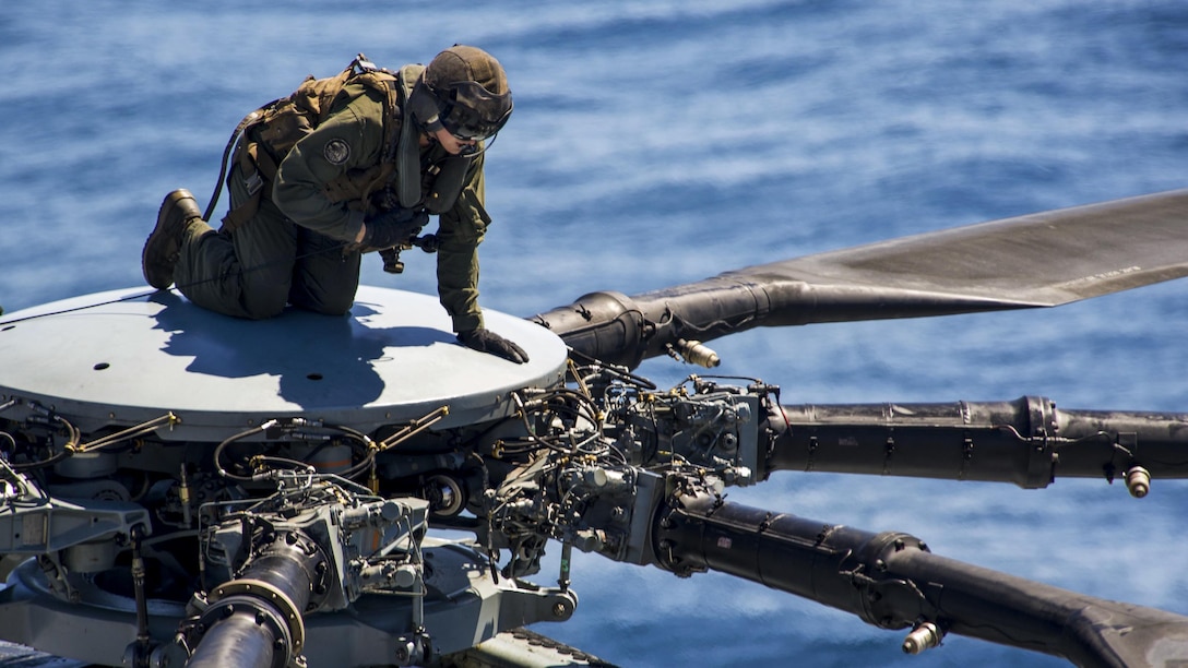 A Marine climbs to the top of a CH-53E Super Stallion to conduct maintenance during flight operations on the USS America in the Pacific Ocean, March 29, 2017. The America is underway with more than 1,000 sailors and 1,600 embarked Marines conducting Integration operations to prepare for the ship’s maiden deployment later this year. The Marine is assigned to Marine Medium Tiltrotor Squadron 161. Navy photo taken by Seaman Apprentice Chad Swysgood