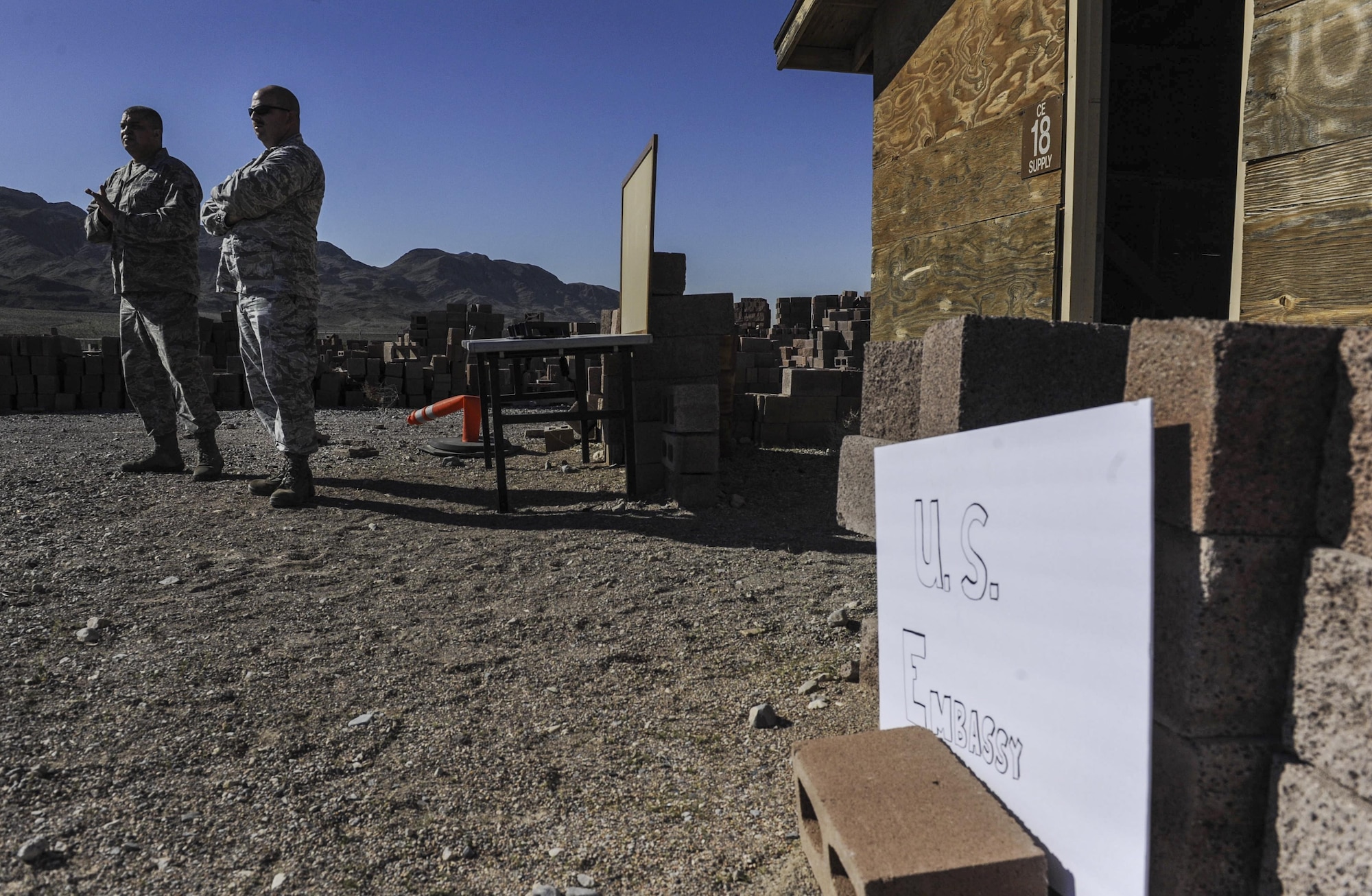 Senior leadership waits outside a simulated U.S. Embassy for Airmen from multiple teams to speak with simulated vendors during a 99th Contracting Squadron training exercise on Nellis Air Force Base, Nev., March 16, 2017. The 99th CONS coordinated and hosted this exercise, bringing contracting personnel from five separate bases to participate. (U.S. Air Force photo by Airman 1st Class Kevin Tanenbaum/Released)