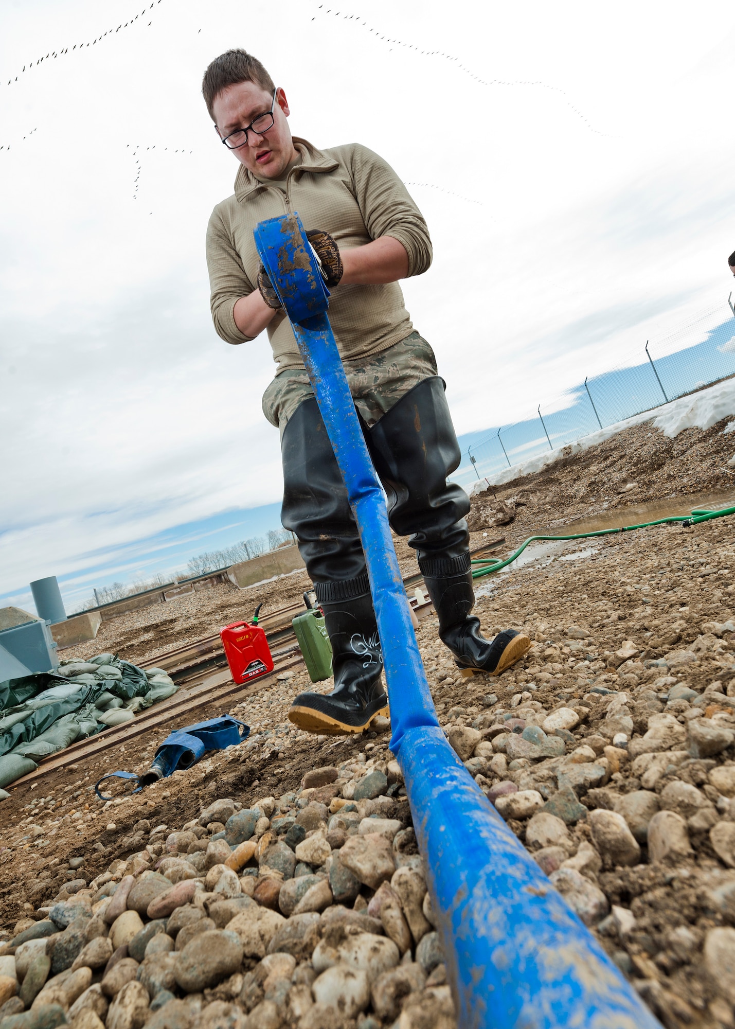 Senior Airman Matthew Singer, 91st Missile Maintenance Squadron electromechanical team technician, winds up a hose near Bowbells, N.D., March 29, 2017. The electromechanical team technicians measured rising water levels and relocated water, snow and mud away from critical 91st MW assets. (U.S Air Force photo/Senior Airman J.T. Armstrong)