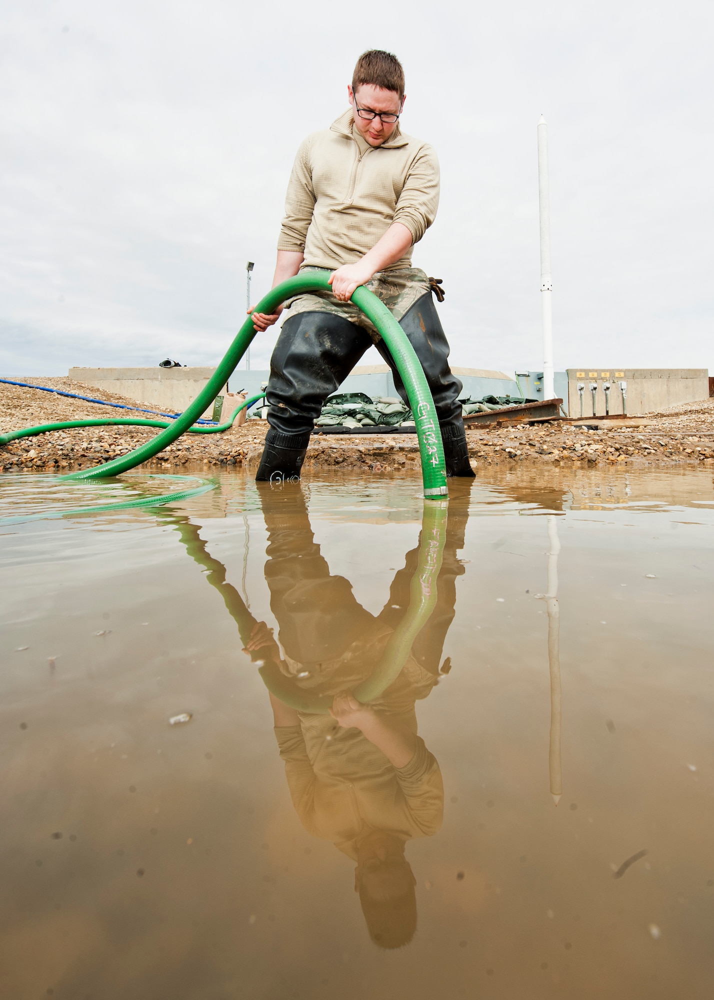 Senior Airman Matthew Singer, 91st Missile Maintenance Squadron electromechanical team technician, finishes draining flood-water from a launch facility near Bowbells, N.D., March 29, 2017. Singer used a water-pump and hose to drain and relocate water to a safe level. (U.S Air Force photo/Senior Airman J.T. Armstrong)