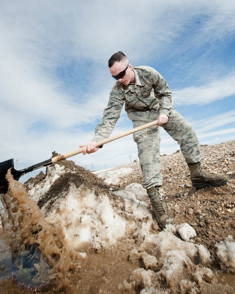 Airman 1st Class Heath Rauch, 91st Missile Maintenance Squadron electromechanical team technician, shovels snow and mud at a launch facility near Bowbells, N.D., March 29, 2017. Rauch was a part of a two-man team responsible for relocating flood-water away from critical assets at the launch facility. (U.S Air Force photo/Senior Airman J.T. Armstrong)