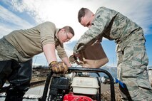 Airman 1st Class Heath Rauch, 91st Missile Maintenance Squadron electromechanical team technician, pours water into a pump near Bowbells, N.D., March 29, 2017. The two-man team used a water-pump to relocate flood-water away from critical assets at the launch facility. (U.S Air Force photo/Senior Airman J.T. Armstrong)