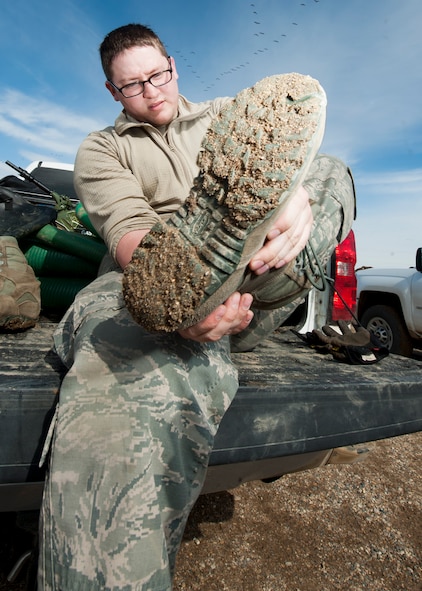 Senior Airman Matthew Singer, 91st Missile Maintenance Squadron electromechanical team technician, removes his boot at a launch facility near Bowbells, N.D., March 29, 2017. Singer was a part of a two-man team responsible for relocating flood-water away from critical assets at the launch facility. (U.S Air Force photo/Senior Airman J.T. Armstrong)