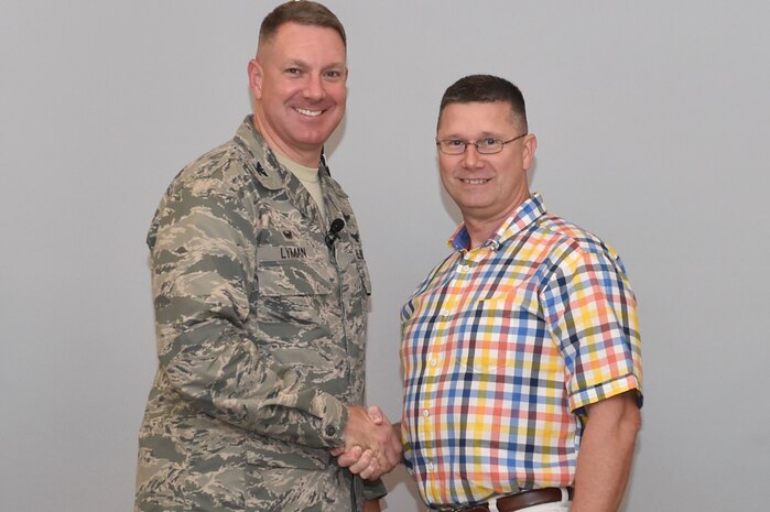 Col. Robert Lyman, left, 628th Air Base Wing commander, congratulates Patrick Miller, right, 628th Medical Group dental hygienist, for his work during National Children’s Dental Month during a commander’s call at Joint Base Charleston, South Carolina, March 29, 2017. Miller worked with three elementary schools, the Child Development Center and the youth center to educate them on proper oral hygiene. 