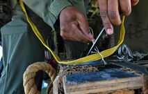 U.S. Air Force Senior Master Sgt. Christopher Minnifield, 37th Airlift Squadron readiness superintendent, cuts excess cotton string from a knot around the rip cord of a parachute during Exercise Stolen Cerberus IV at Elefsis Air Base, Greece, April 24, 2017. The cotton string provides a barrier between two nylon straps, which generate heat when rubbed together and could damage the cord. Approximately 110 Airmen and three C-130s from the 86th Airlift Wing’s 37th AS, Ramstein Air Base, Germany, participated in Exercise Stolen Cerberus IV with the Hellenic air force and the U.S. Army from April 18 to 28. (U.S Air Force photo by Senior Airman Tryphena Mayhugh)