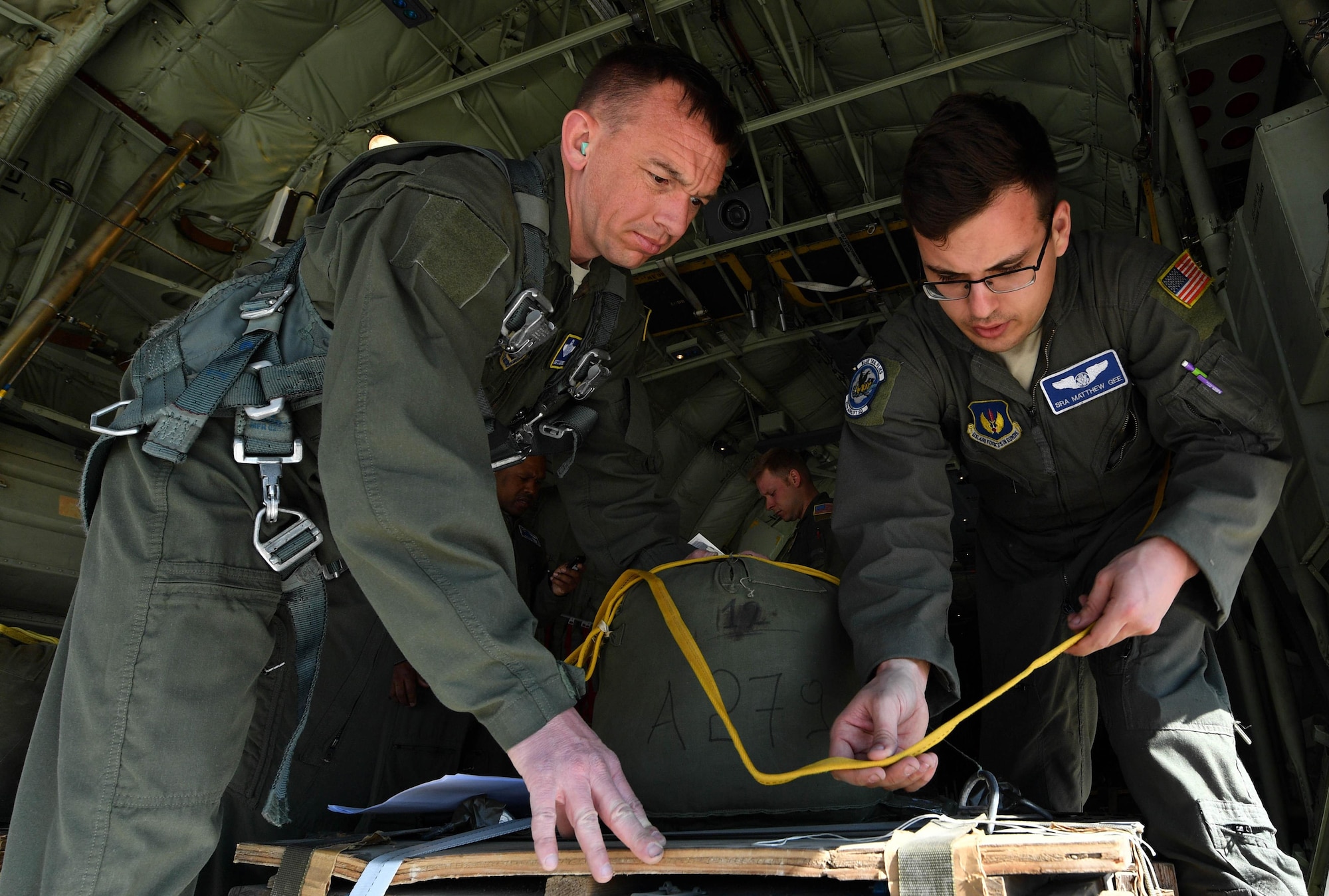 U.S. Air Force Senior Airman Matthew Gee, 37th Airlift Squadron loadmaster, prepares a low-cost low-altitude cargo for an air drop while Master Sgt. CJ Campbell, 37th AS aircraft loadmaster, supervises during Exercise Stolen Cerberus IV at Elefsis Air Base, Greece, April 19, 2017. Gee, Campbell, and another loadmaster worked with the Hellenic air force to set up four LCLA cargos for a drop. Combined exercises such as these enhance the interoperability capabilities and skills among allied and partner armed forces. (U.S Air Force photo by Senior Airman Tryphena Mayhugh)