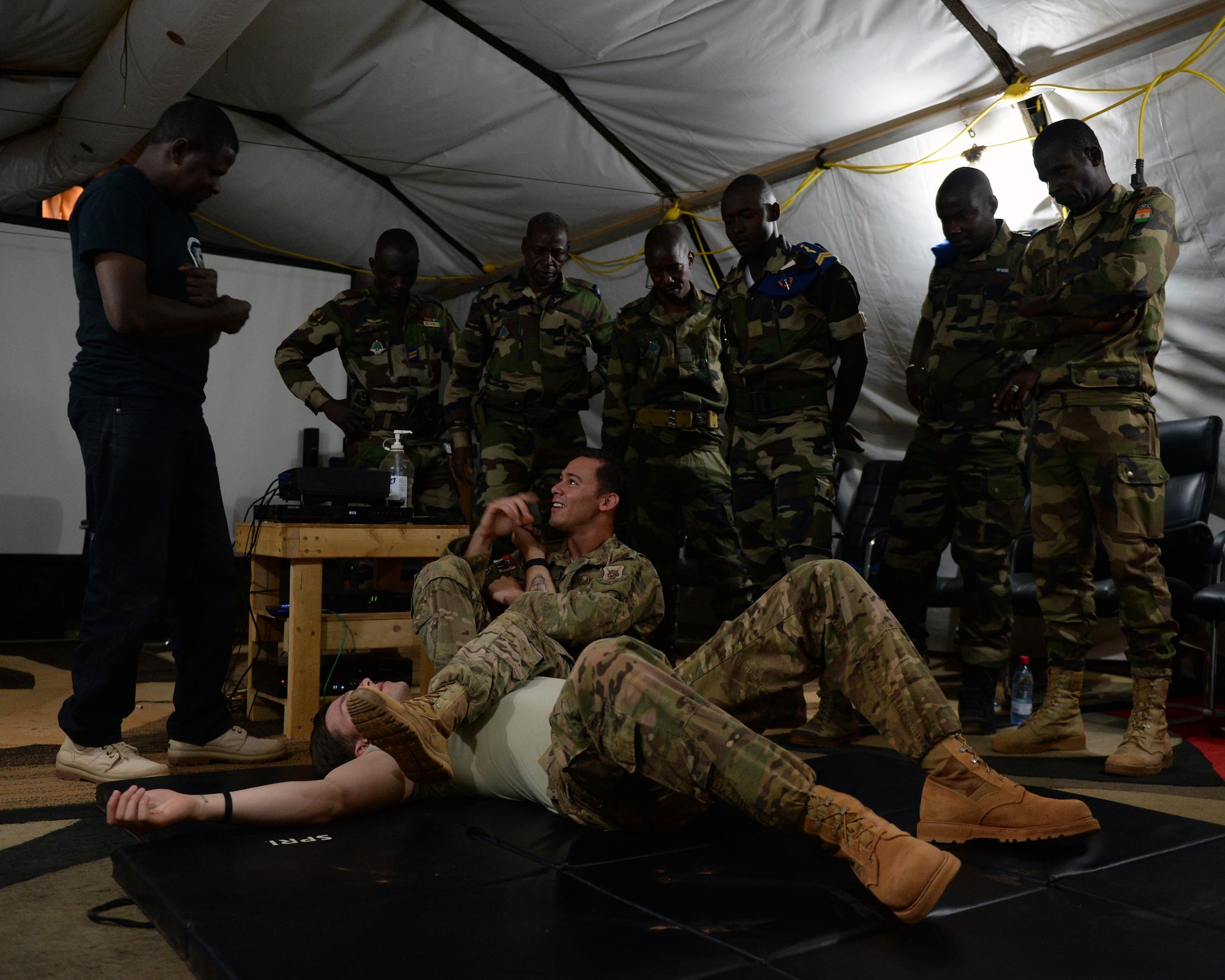Members of the Forces Armées Nigeriennes watch as Senior Airman Joshua Brooks, 768th Expeditionary Air Base Squadron air advisor, demonstrates an armbar at Nigerien Air Base 101, Niger, April 4, 2017. The training was part of a larger joint knowledge exchange to help train and build relations with the FAN. (U.S. Air Force photo by Senior Airman Jimmie D. Pike)