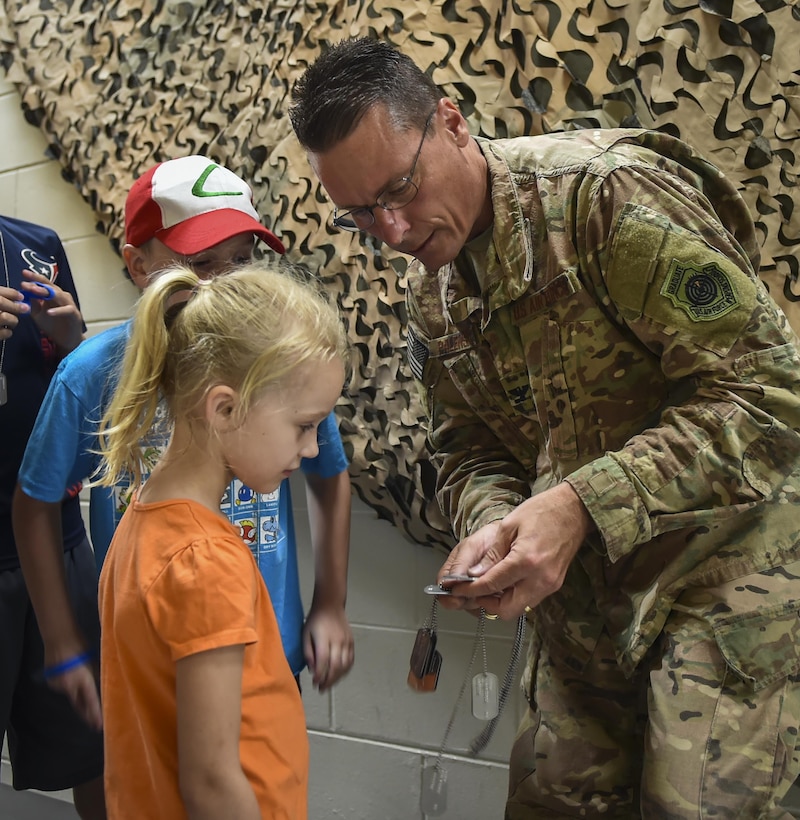 Col. Tom Palenske, the commander of the 1st Special Operations Wing, helps military children find their dog tags during Operation Kids Understanding Deployment Operations at Hurlburt Field, Fla., April 22, 2017. Children processed through a deployment line where they received dog tags, shirts and deployment bags. (U.S. Air Force photo by Airman 1st Class Joseph Pick)