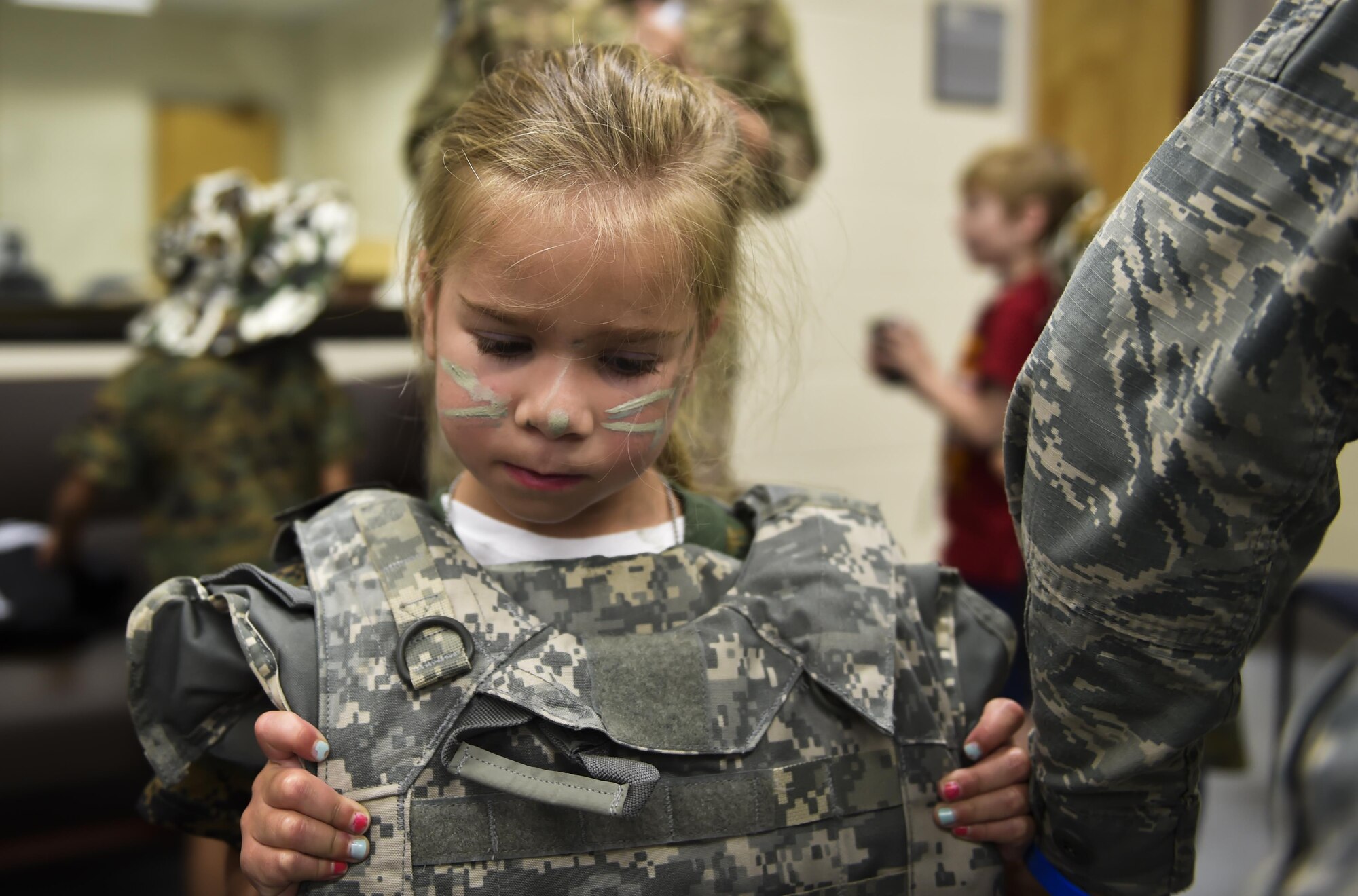 A military child puts on a vest before deploying during Operation Kids Understanding Deployment Operations at Hurlburt Field, Fla., April 22, 2017. Operation KUDOS is an educational event aimed to help build resilience in military youth by engaging them in activities that simulate the pre-deployment experience, such as pre-deployment lines and demonstrations. (U.S. Air Force photo by Airman 1st Class Joseph Pick)