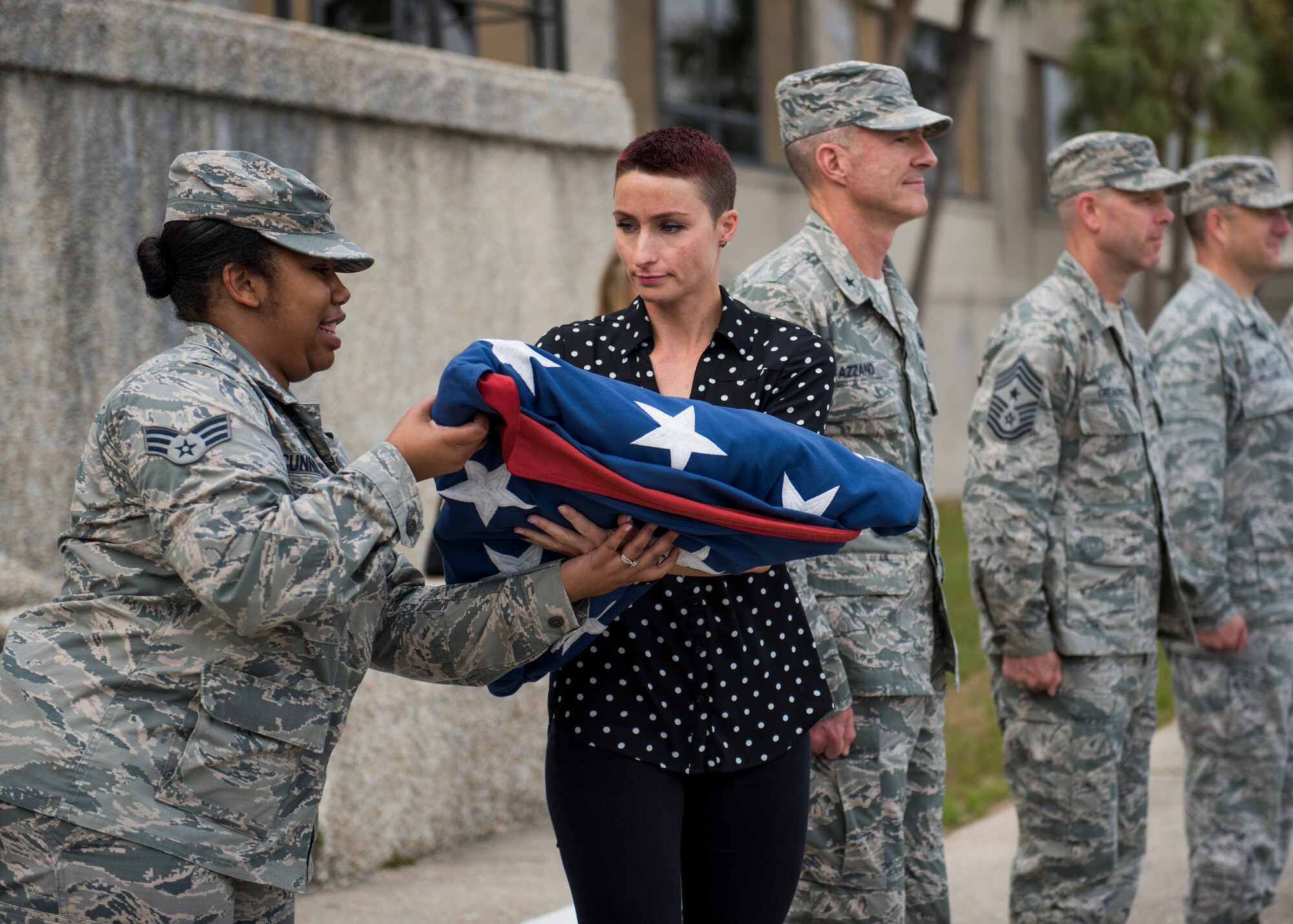 Esther Quast, 96th Logistics Readiness Squadron, passes the flag to Senior Airman Kaisha Cunningham, 96th Test Wing, during the all-civilian retreat ceremony April 27 at Eglin Air Force Base, Fla. The all civilian retreat is held to show support for our military members. (U.S. Air Force photo/Ilka Cole)